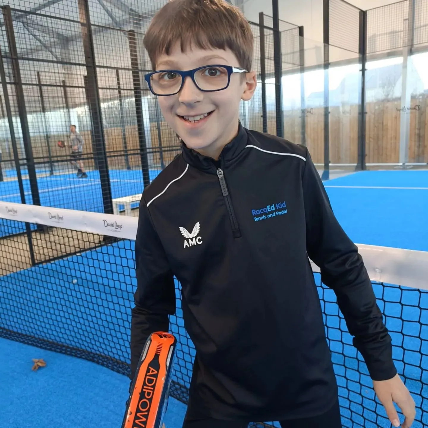 A smiling RacqEd Kid on the padel court